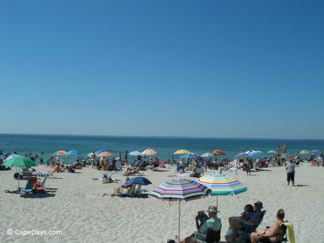 People on the beach, striped sun umbrellas and beautiful blue water