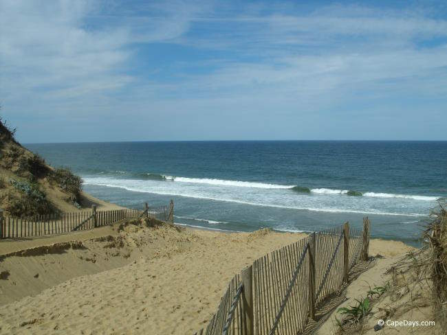 Fenced path between the dunes, leading to the ocean and rolling waves