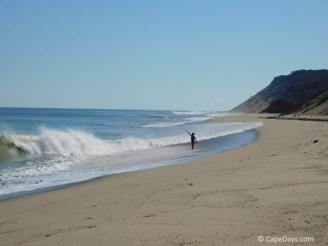 Woman doing yoga on the beach, windblown waves breaking on the shoreline at Ballston Beach
