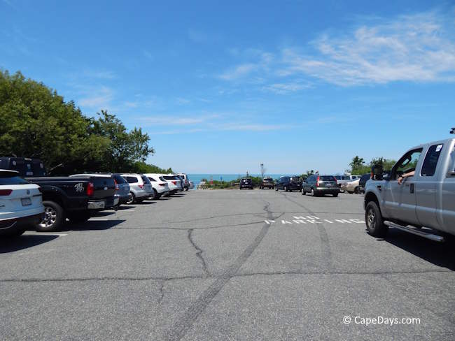 Beach parking lot with a few parked cars and a view of the ocean beyond Beach parking lot with a few parked cars and a view of the ocean beyond