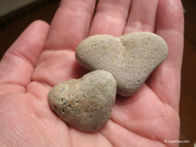 Two small heart-shaped stones in the palm of a lady's hand