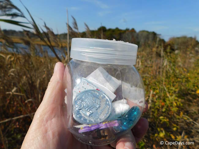 Small, clear plastic container with trinkets and little hand-written notes inside