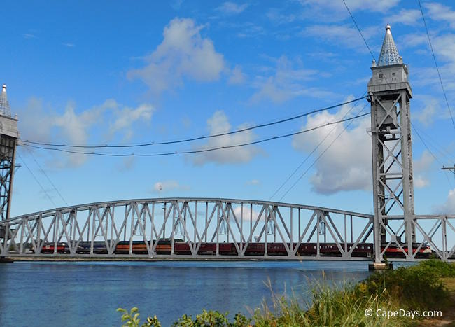 Distant view of Cape Cod Canal Railroad Bridge with lift span lowered and train crossing