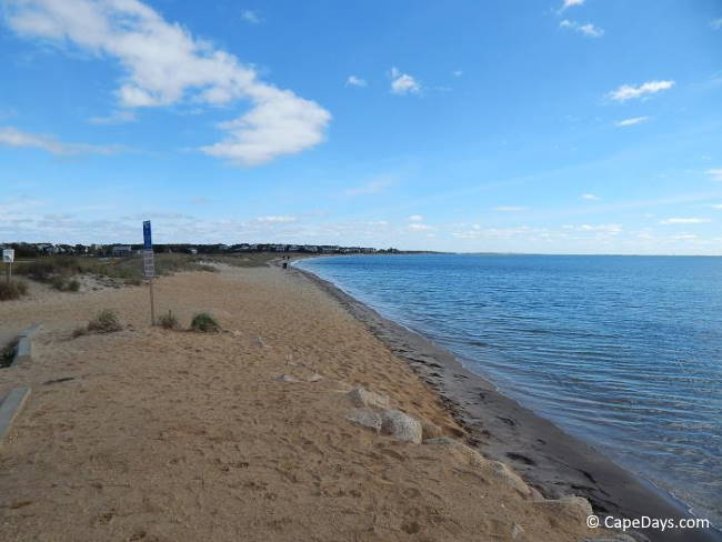 Gentle waves lapping at the shore, footprints in the sand, pretty blue sky and ocean.