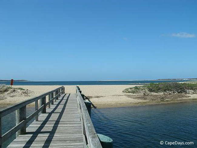 Boardwalk over a saltwater inlet, views of the sand and calm blue ocean
