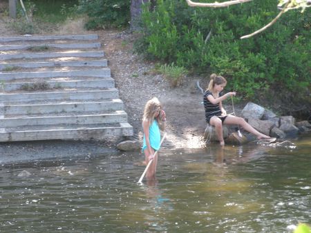 Two girls in swimsuits, fishing for blue crabs