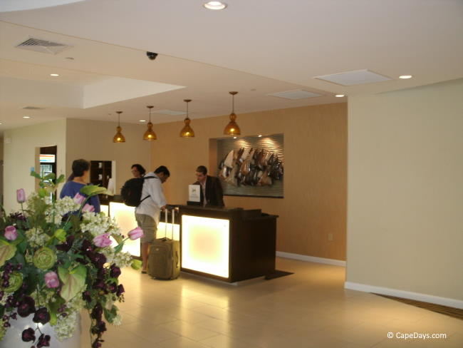 Inside a hotel lobby, beautiful floral bouquet, guests registering at front desk