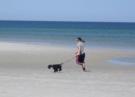 ケープコッド湾のビーチで犬を連れてジョギングする女性