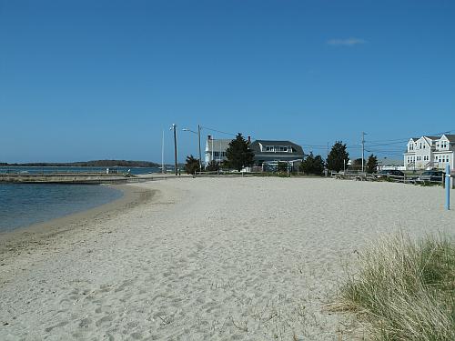 Clear blue sky, wide stretch of beach, jetty and waterfront homes