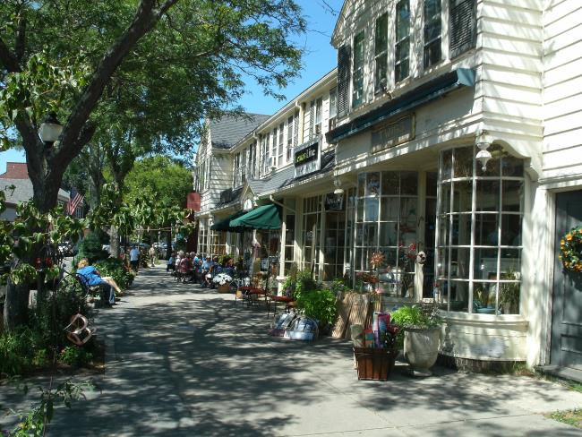 View of quaint shops along a tree-lined sidewalk on Main Street in Falmouth Village