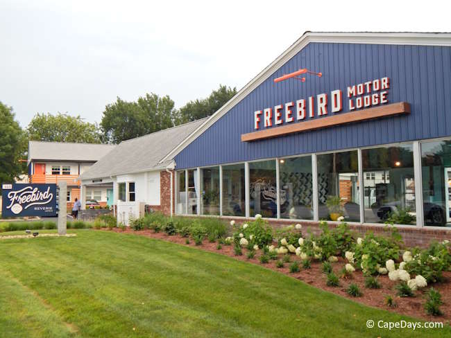 Low-rise lodging building with blue siding, large windows, and landscaped lawn in West Yarmouth on Cape Cod.