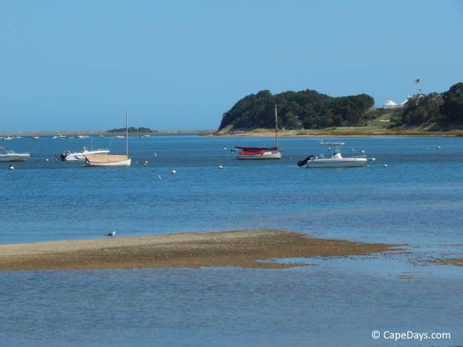 View of the bay, sandbar, and white party tents on knoll in the dostance