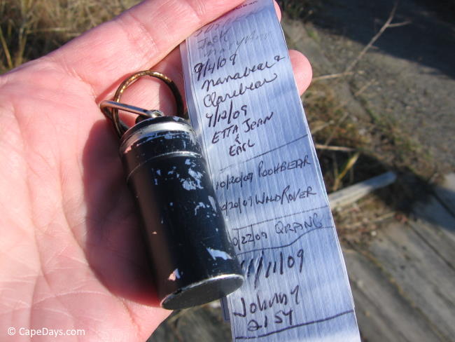 Old, scratched-up black tube and an un-rolled note pad with names and dates of previous cache finders