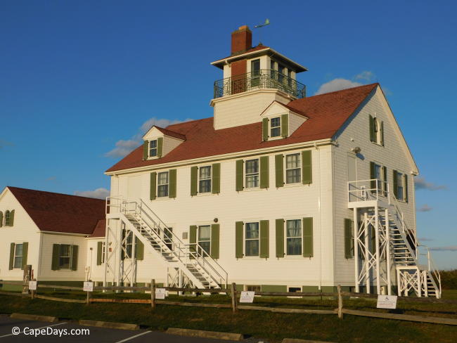 Large white Coast Guard building with green shutters, overlooking the beach Large white Coast Guard building with green shutters, overlooking the beach