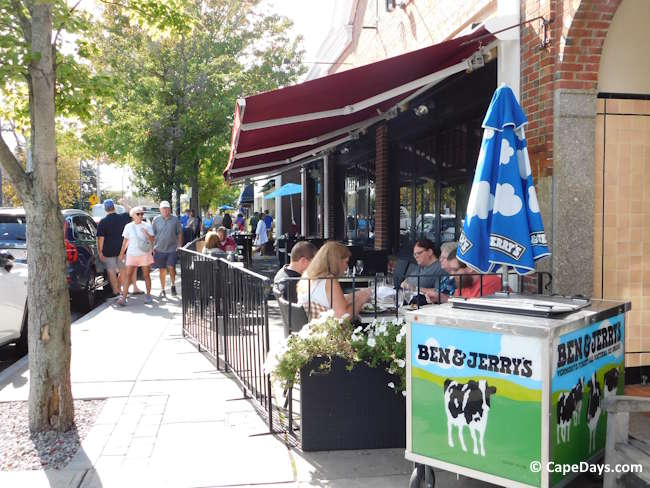 People dining outdoors along Main Street in Hyannis. Ben & Jerry's ice cream cart on the sidewalk.