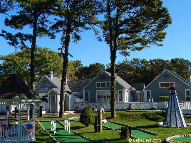 Mini golf course at Popponesset Marketplace with lighthouse, gazebo, and Cape-style buildings