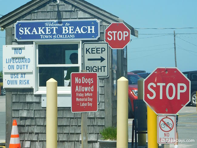 Weathered shingled entry booth at Skaket Beach in Orleans, with stop signs and lifeguard duty status posted outside