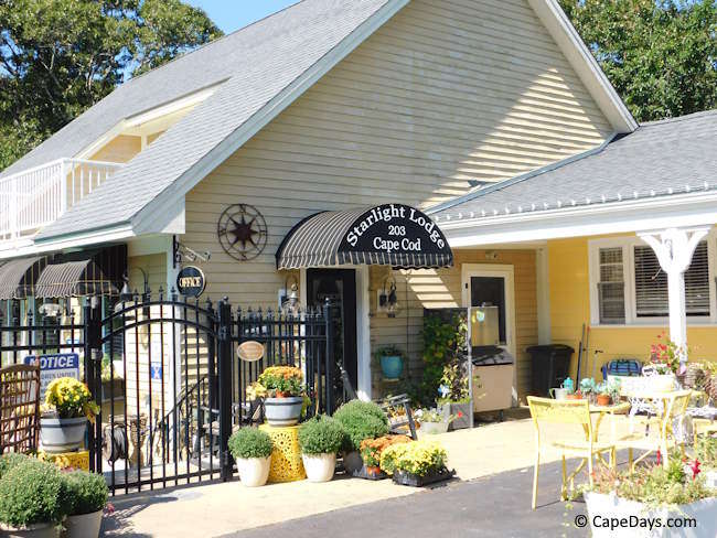 Yellow-sided building with black awning over entryway with lettering: "Starlight Lodge Cape Cod" Yellow-sided building with black awning over entryway with lettering: "Starlight Lodge Cape Cod"