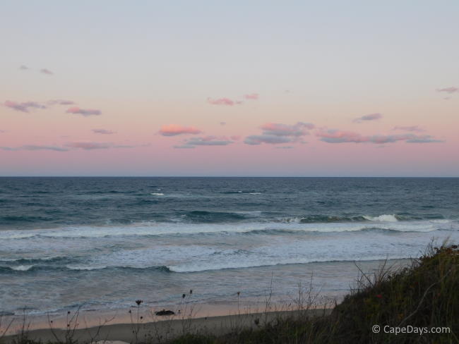 Rolling waves hitting the shore, pastel sunset sky over the ocean Rolling waves hitting the shore, pastel sunset sky over the ocean