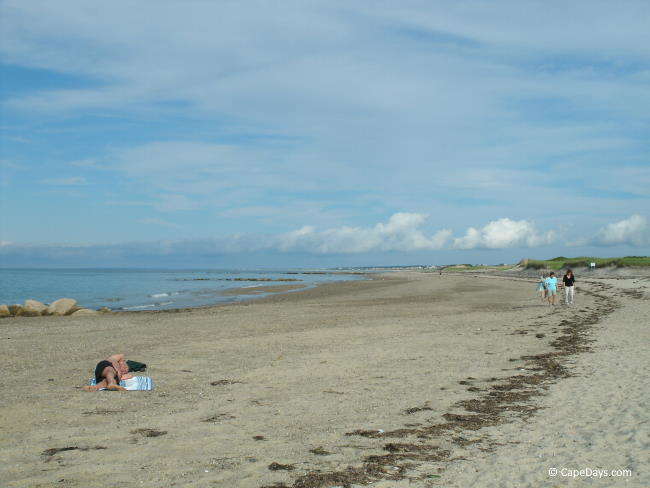 Man relaxing and people walking on beach
