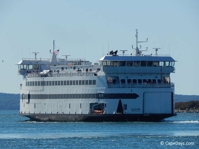 Large, multi-deck ferry exiting channel, passing rock jetty, going to open water