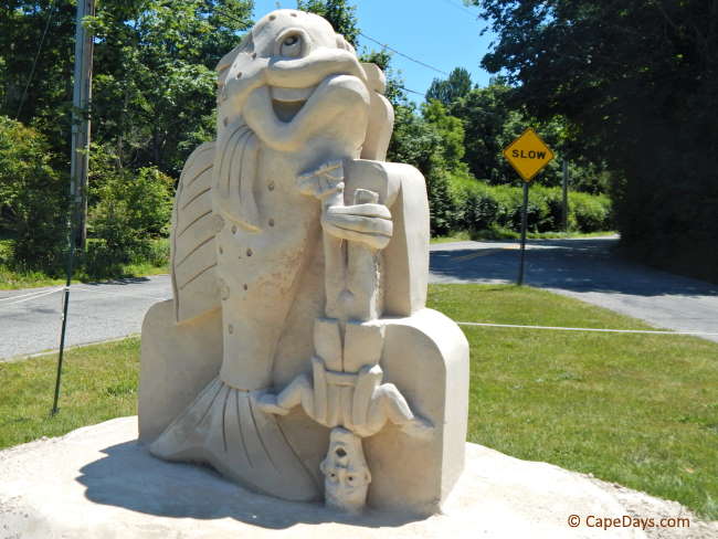 Humorous sand sculpture of a large fish holding his "catch"